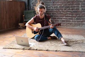 caucasiano jovem adulto Aprendendo guitarra conectados música classe com distante professor computador Móvel dispositivo foto