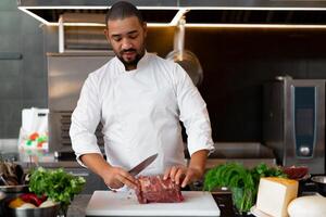 bonito jovem africano chefe de cozinha em pé dentro profissional cozinha dentro restaurante preparando uma refeição do carne e queijo legumes. foto