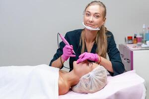 cosmetologia gabinete cliente mentiras em sofá. esteticista aplica-se marcação em sobrancelhas. foto