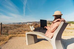 viajante com dela computador portátil sentado em a Mediterrâneo costa do barcelona. foto