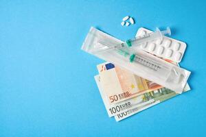 pílulas esvaziar bolhas para drogas Individual seringa e dinheiro mentira em uma azul fundo foto