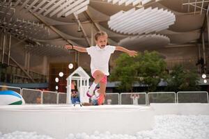 feliz pequeno menina jogando branco plástico bolas piscina dentro diversão parque. Parque infantil para crianças. foto