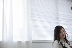 uma relaxado japonês mulher de controlo remoto trabalhos dentro a casa escritório foto