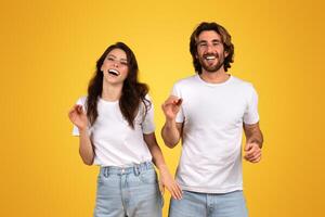 radiante jovem mulher e homem dentro branco tees rindo e dançando foto