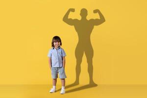 uma alegre jovem criança carrinhos sorridente com uma confiante, muscular Super heroi sombra fundida foto