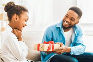 afro-americano pai dando presente para filha às casa foto