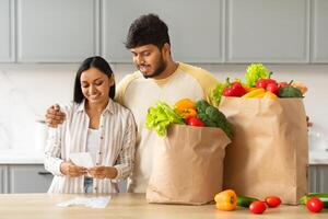 feliz indiano casal com saco cheio do Comida verificação conta foto