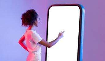 Preto senhora interagindo com ampla Smartphone tela em gradiente pano de fundo foto