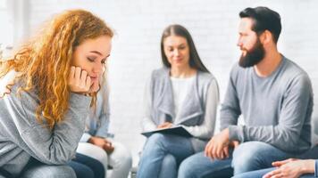 chateado ruiva mulher sentado às grupo terapia sessão foto