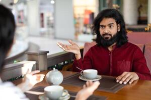 confuso indiano homem olhando às dele namorada e gesticulando foto