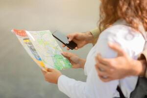 fechar-se do turista casal segurando colorida cidade mapa e Smartphone foto