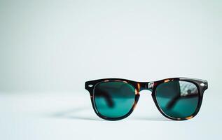 ai gerado clássico oculos de sol com gradiente lentes sentado em uma branco superfície foto
