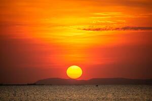 pôr do sol sobre ilha laranja vermelho céu com Sol brilho raio passar laranja nuvem dentro a tarde foto