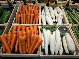 fresco cenoura e branco rabanete exibição dentro uma de madeira caixa. fresco legumes vendido dentro a noite mercado. foto