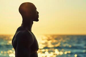 ai gerado silhueta do uma homem dentro pacífico contemplação contra uma dourado pôr do sol sobre a oceano foto