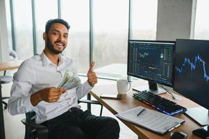 jovem indiano o negócio homem comerciante olhando às computador tela com negociação gráficos refletindo dentro Óculos assistindo estoque negociação mercado financeiro dados crescimento conceito, fechar acima. foto