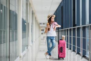 pequeno adorável criança dentro aeroporto esperando para embarque dentro de casa. adorável pequeno menina às aeroporto come velozes Comida e bebidas chá foto