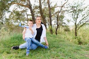 feliz jovem mãe é jogando com dela bebê dentro uma parque em uma verde grama. felicidade e harmonia do família vida. ótimo família período de férias. Boa fim de semana. mães dia. feriado. a conceito do uma feliz família foto