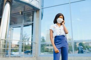 fechar acima jovem Afro-Americano empresária vestindo protegendo mascarar, encarando às a Câmera. foto