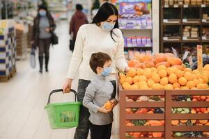 autêntico tiro do mãe e filho vestindo médico máscaras para proteger si mesmos a partir de doença enquanto compras para mercearias juntos dentro supermercado foto