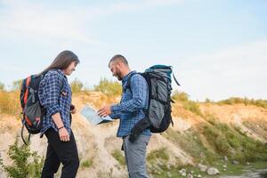 dois mochileiros desfrutando cenário natureza Visão enquanto caminhada dentro nacional parque. casal do caminhantes planejamento Próximo caminho para explorar segurando mapa durante viagem. infográficos ilustração mapa com topo destinos foto