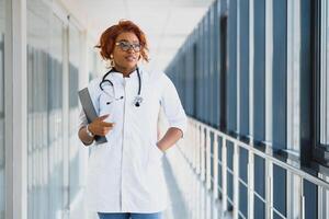 retrato do bonita africano médico doutor. africano americano médico dentro moderno clínica foto