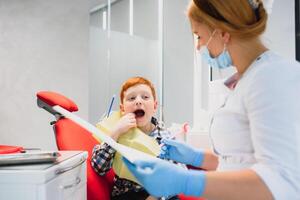 dentista vestindo mascarar. ruivo criança dentista vestindo mascarar examinando fofa Garoto foto