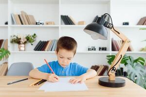 Educação, infância, pessoas, dever de casa e escola conceito - sorridente aluna Garoto com livro escrevendo para caderno às casa foto