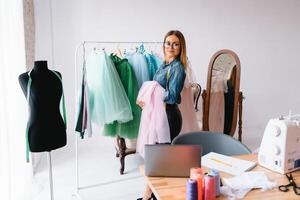 trabalhando em Novo coleção. Novo ordem. fêmea moda desenhador trabalho em a Novo roupas dentro a oficina. foto