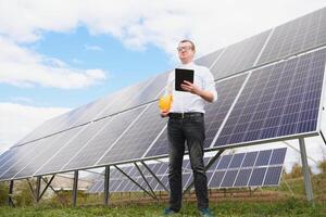 solar energia. jovem o negócio homem dentro uma branco camisa perto a solar painéis para poder plantas. foto