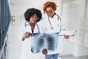 africano médicos olhando às pacientes raio X às hospital foto