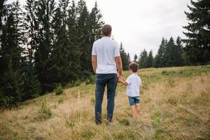 pai e criança caminhada dentro cênico montanhas. Papai e filho desfrutando a Visão a partir de a montanha topo dentro cárpato montanhas foto