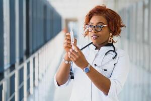 africano americano fêmea médico segurando seringa com injeção foto