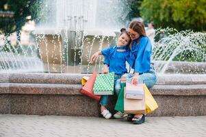 oferta, consumismo e pessoas conceito - feliz jovem mulheres dela Dauther com compras bolsas caminhando cidade rua foto