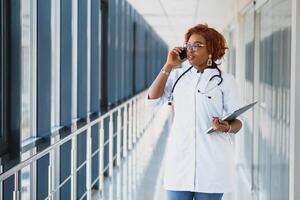 retrato do africano fêmea médico às local de trabalho foto