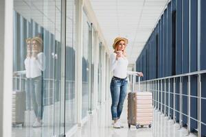jovem bonita à moda mulher com bagagem às a internacional aeroporto. esperando dela voar às imposto livre compras zona. foto