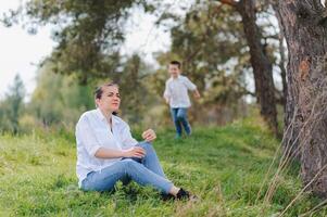 elegante mãe e bonito filho tendo Diversão em a natureza. feliz família conceito. beleza natureza cena com família ao ar livre estilo de vida. feliz família em repouso junto. felicidade dentro família vida. mães dia. foto