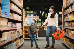 mãe e dela filho vestindo protetora face mascarar fazer compras às uma supermercado durante a coronavírus epidemia. foto