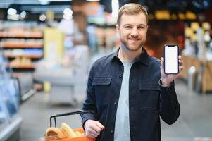 homem usando Smartphone dentro supermercado. foto