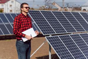 solar painéis. homem em pé perto solar painéis foto