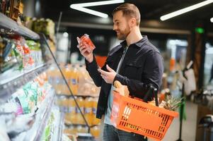 jovem homem comprando mercearias às a supermercado. de outros clientes dentro fundo. consumismo conceito. foto