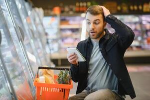 jovem homem compras dentro mercearia loja. compras conceito foto