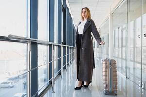 retrato do bem sucedido o negócio mulher viajando com caso às aeroporto. lindo à moda fêmea viagem com bagagem. foto