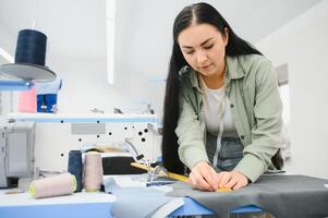 jovem mulher trabalhando Como costureira dentro roupas fábrica. foto