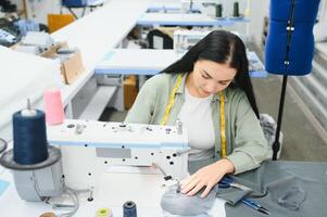 positivo jovem mulher de costura com profissional máquina às oficina. foto