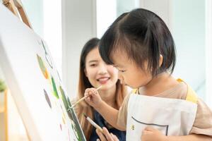 feliz Ásia mãe jogando Aprendendo pintura para pequeno garota. engraçado família é feliz e animado dentro a casa. mãe e filha tendo Diversão gastos Tempo junto. feriado, atividade foto