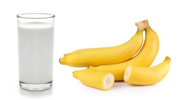 leite fresco no copo e banana no fundo branco foto