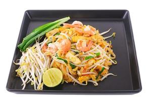 comida tailandesa pad thai, frite macarrão com camarão no prato preto foto