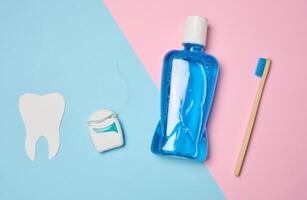 plástico garrafa com enxaguatório bucal, de madeira escova de dente em azul fundo foto