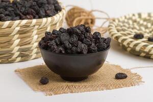 seco Preto uvas servido dentro tigela isolado em guardanapo lado Visão do seco frutas em cinzento fundo foto